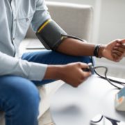 Unrecognizable African Guy Measuring Arterial Pressure Having Hypertension Indoor, Cropped
