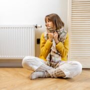 Warmly dressed woman near heater at home
