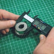 Metal gear measurement process. Factory man, worker measuring steel detail, gear with digital