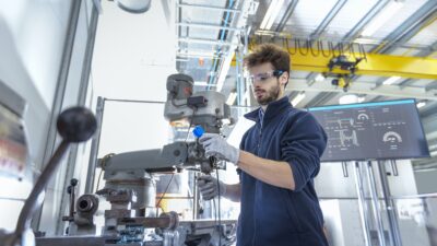 Robotics engineer fitting sensors to traditional engineering lathe in robotics research facility