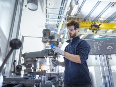 Robotics engineer fitting sensors to traditional engineering lathe in robotics research facility