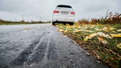 Emergency braking of white car on road outside city.